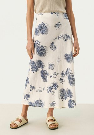 Floraler Midi-Rock in Creme mit blauem botanischen Druck, der ein fließendes Design, eine weiche Textur und seitliche Schlitze für Bewegungsfreiheit aufweist.