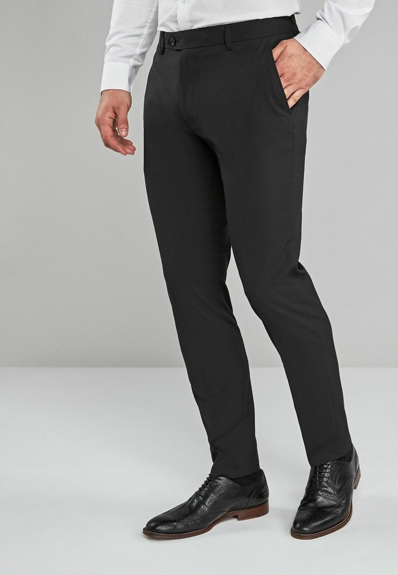 Zwarte dresspants met een slim fit, met een gladde textuur, een straight-leg ontwerp en een knoopsluiting, gecombineerd met zwarte leren dresschoenen.