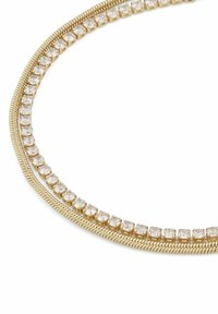 Nackband i guldton med två sammanflätade strängar. Den ena strängen har en slät, vriden textur, medan den andra pryds av glittrande klara rhinstenar.