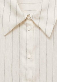 Chemise à col blanc avec fines rayures verticales noires et trois boutons blancs visibles sur le devant.