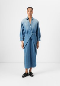 Denim skjortekjole med lange ermer, knappestolpe foran og omslagdesignet. Lys til mørk blå gradient, glatt tekstur og ankellengde.