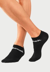 Schwarze Knöchelsocken aus weichem Material mit einem gerippten Bündchen und dem weißen "bench."-Logo an der Seite. Glatte Textur, niedrig geschnittenes Design.