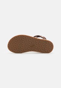 Brown rubber sandal sole with a geometric pattern. Features contrasting straps and logo detail. Lightweight and flexible design.