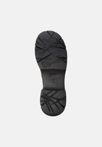 Black shoe sole with pronounced tread pattern, featuring deep grooves and cross-hatch designs for traction. Includes size label.