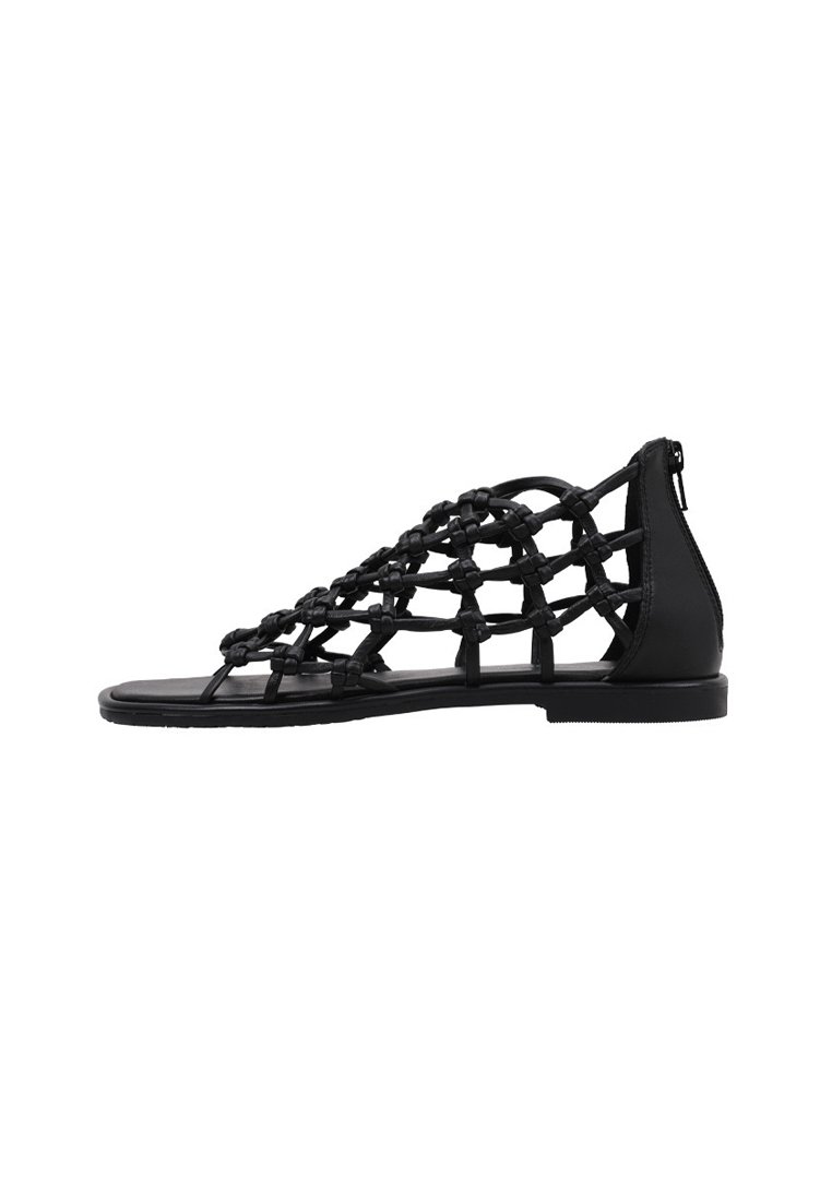 Sandalias negras con un diseño de tira trenzada, suela plana, textura suave y cierre con cremallera en la parte posterior. Estructura minimalista y abierta.