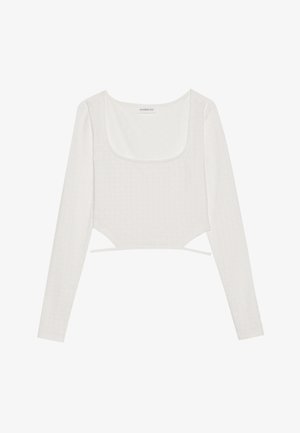 White long-sleeve crop top made from textured fabric with a square neckline and side ties, featuring subtle pattern details.
