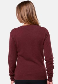 Pull bourgogne à manches longues, col rond et texture lisse, avec des poignets et un ourlet côtelés, vu de l'arrière.