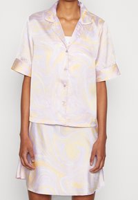 Kortärmad, kragsätt med pyjamas i lila med gula och vita svängningar. Sidenmaterial med knapp-up topp och svängd kjol.