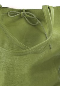Groene lederen tote bag met een textuurafwerking, voorzien van lange handvatten en een gestrengelde sluiting. Heeft een zachte, slungelige vorm.