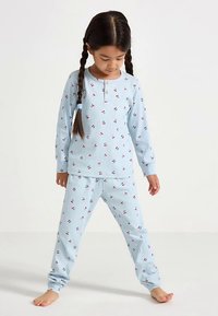 Ensemble de pyjama bleu clair côtelé avec imprimé cerises. Haut à manches longues avec fermeture à boutons et pantalon assorti. Tissu doux, coupe décontractée.