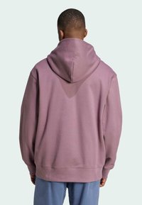 Pullover hoodie i mjuk lavendelfärgad tyg, med en stor huva, ribbade ärmmuddar och en avslappnad passform. Slät textur med minimal detaljer.