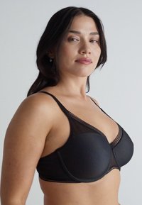 Schwarzer Netz-BH mit geformten Cups, verstellbaren Trägern und einem strukturierten Muster. Gestaltet mit transparenten Akzenten und einem glatten Bund.