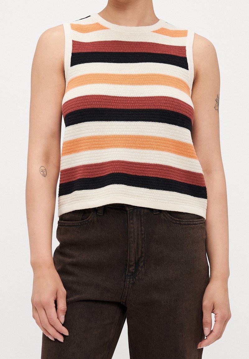 Haut sans manches en maille à rayures horizontales crème, noir, rouille et orange, porté avec un pantalon taille haute marron foncé.
