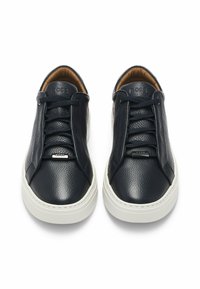 Black leather sneakers with textured finish, featuring a rounded toe, white rubber sole, and lace closure. Logo detail on the tongue.