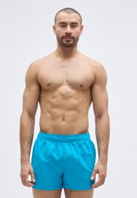 Calções de banho masculinos em turquesa vibrante, com cintura elástica e tecido leve e suave. Corte curto, sem padrões ou detalhes.