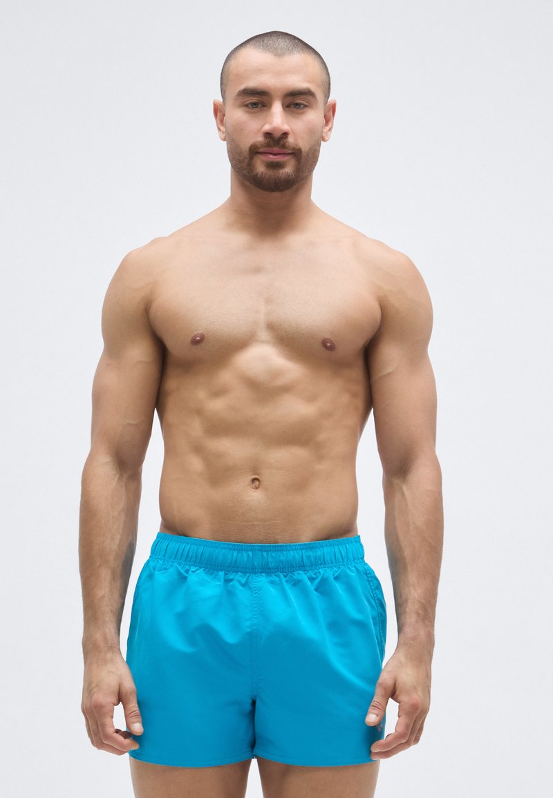 Calções de banho masculinos em turquesa vibrante, com cintura elástica e tecido leve e suave. Corte curto, sem padrões ou detalhes.