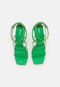 Sandali alta apertura con tacco verde, con punta quadrata, caratterizzati da sottili cinturini e una finitura lucida. Internamente etichettati "MICHAEL KORS."