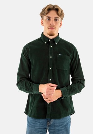 Groene corduroy knoopshirt met een borstzak, voorzien van een klassieke kraag en witte knopen, gecombineerd met een blauwe spijkerbroek.
