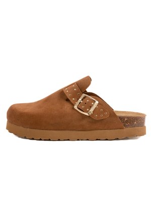 Sabot en suede marron avec un bout arrondi, une sangle à boucle réglable et un semelle en liège texturé. Dispose d'une semelle en caoutchouc épaisse avec adhérence.