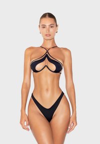 Black bikini set featuring a cut-out design, thin straps, and minimal coverage. Smooth texture with contrasting detailing around the edges.