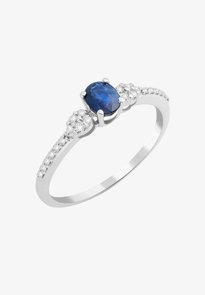 Anello d'argento con una gemma ovale blu al centro, fiancheggiato da piccole pietre tonde chiare lungo la fascia per un tocco di luminosità.
