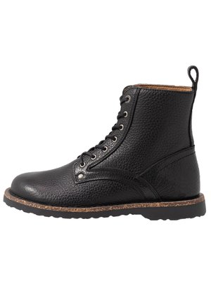 Czarne skórzane botki na sznurowadła z teksturowaną powierzchnią, okrągłym noskiem i korkową podeszwą. Posiadają metalowe przelotki i tylną pętlę ułatwiającą zakładanie.