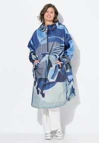 Sininen ja harmaa vedenpitävä poncho abstraktilla hevossuunnitelmalla, huppu ja suuret etutaskut. Sileä rakenne ja ylisuuri malli.