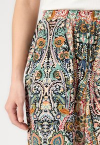 Floral-patterned skirt featuring vibrant colors on a black background. Made of lightweight fabric, it has a pleated design and an elastic waistband.