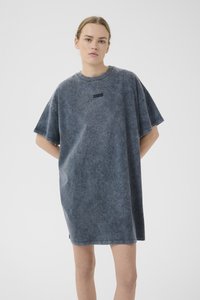 Per didelę T-shirt suknelę blukinto mėlyno džinsinio stiliaus, turinčią trumpas rankoves, apvalią iškirptę ir mažą juodą logotipo detalę ant krūtinės.