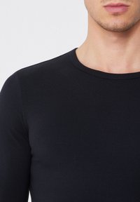 Schwarzes Langarmshirt mit rundem Halsausschnitt, aus glattem Stoff, mit taillierter Passform und sanfter Textur. Keine sichtbaren Logos oder Muster.