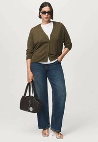 Olive green cardigan with buttons, white shirt underneath, blue wide-leg jeans, black handbag, and white heeled sandals. Black sunglasses.