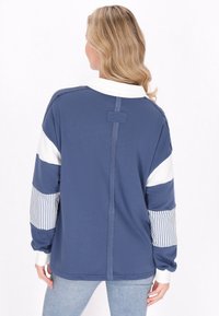 Pullover blu navy con maniche bianche e strisce; vestibilità comoda; scollo a costine; dettaglio sulla cucitura posteriore; morbida texture del tessuto.