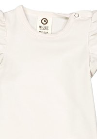Top per neonati in cotone bianco con maniche corte a volant, scollatura rotonda e chiusura a pressione sulla spalla. Etichetta del brand visibile all'interno.