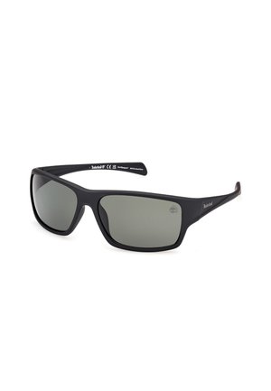 Timberland-Sonnenbrille mit schwarzem mattem Rahmen, grau getönten Gläsern, geschwungener Form und Logo an der Fassung. Robustes und leichtes Design.