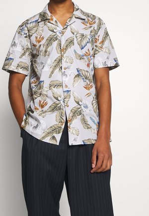 Chemise à manches courtes avec un fond blanc ornée d'un motif de feuilles et de fleurs tropicales dans des tons de vert, orange et bleu ; fermeture à boutons.