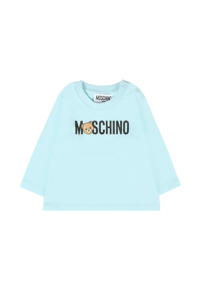 Chemise en coton bleu clair à manches longues avec un graphique d'ours et le texte "MOSCHINO" en noir. Comprend des boutons-pression sur les épaules pour un habillage facile.