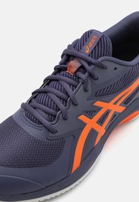 Baskets de course navy avec des accents orange, dotées d'un dessus en mesh texturé, d'un col rembourré et d'une semelle extérieure en caoutchouc pour une meilleure traction.