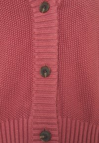 Sweter na drutach w stonowanym różu, z teksturowanymi wzorami, prążkowanymi krawędziami i ciemnobrązowymi guzikami na przednim pasku.