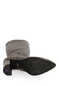 Botín de cuero marrón hasta el tobillo con punta afilada, parte superior texturizada y tacón anguloso. Presenta una suela de goma negra con un acento morado.