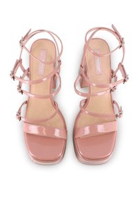 Sandalias de tacón alto de charol rosa con múltiples tiras entrecruzadas, puntera cuadrada y hebillas ajustables. Textura suave con un acabado brillante.