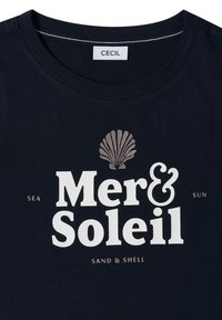 T-shirt bleu marine à col rond, étiqueté "CECIL", avec le texte blanc "Mer & Soleil" et un graphique de coquillage au-dessus, ainsi qu'un texte plus petit "Sea Sun Sand & Shell".