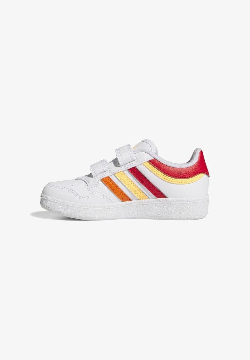 Zapatilla deportiva blanca con franjas en naranja, amarillo y rojo, dos cierres de velcro y suela texturizada, mostrada desde el lado exterior.