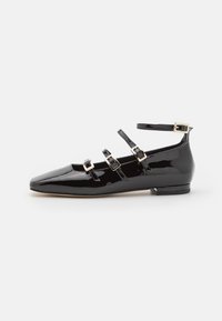 Sorte patent lær flats med spiss tå, tre ankelremmer og gullspenner. Glatt overflate, minimalistisk design, lav blokk hæl.