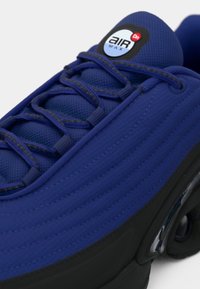 Blue Nike Air Max sneaker with black sole, detailed stitching, and laces, showing the Air Max logo on the tongue.