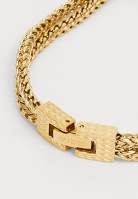 Collana in oro con maglie intrecciate, un elegante chiusura ad anello testurizzata con il nome del marchio inciso per una chiusura sicura e un tocco di stile.