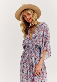 Dlhé modré šaty s paisley vzorom, elastickým pásom, krátkymi rukávmi a hlbokým V-výstrihom. Obsahujú ružové a čierne vzory po celom povrchu. Nosené s širokým klobúkom.