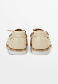 Beige nahka-kengät, joissa on tekstuuri, ruskeat nauhat ja vaaleanruskeat pohjat, joissa on siistit linjat ja pyöreä kärkipohja.