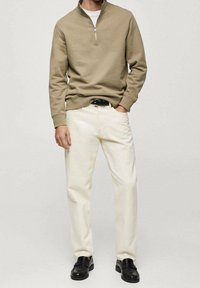 Sweat-shirt à col zippé beige clair, pantalon crème et chaussures noires. Tissu doux, coupe décontractée et texture lisse. Design minimaliste sans motifs.