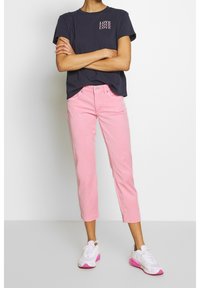 T-shirt marine avec le texte "LOVE", jean rose court et baskets blanches avec accents roses. Les tissus semblent en coton, avec une coupe décontractée.