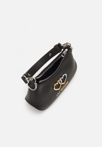 Μαύρη δερμάτινη τσάντα χειρός με κυρτό σχήμα, φερμουάρ, ασημί εξαρτήματα και χρυσό λογότυπο καρδιάς. Διαθέτει κοντό λουρί για μεταφορά.